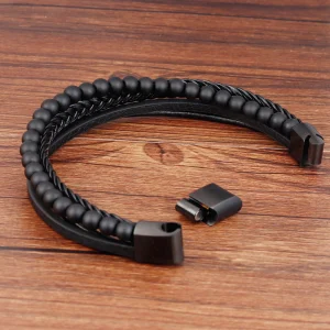 Pulsera de cuero de tres tiras una de ella trenzada y otra con piedras volcánicas y cierre de acero en color negro